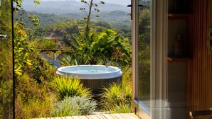 A hot tub surrounded by lush greenery, a wooden deck, and a view of distant mountains. - Ocean view · infinity pool · fully equipped private spa (Playa Grande)