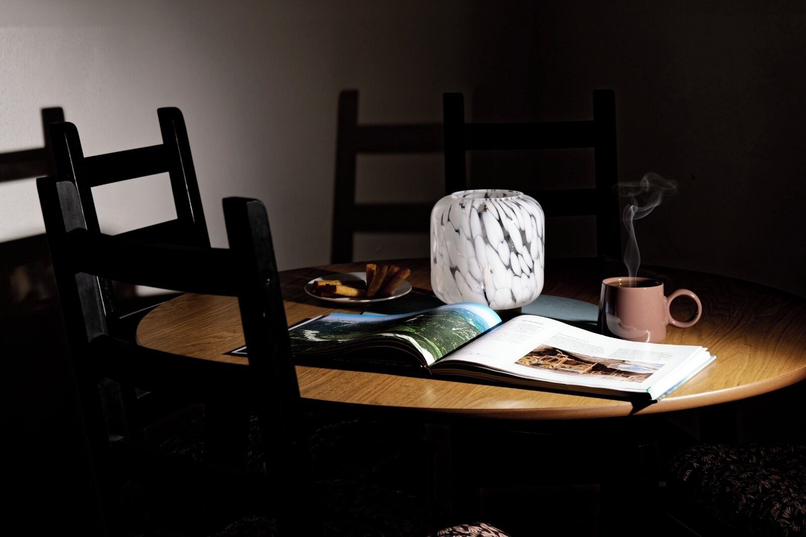 A table with a book, a mug, and a decorative vase.