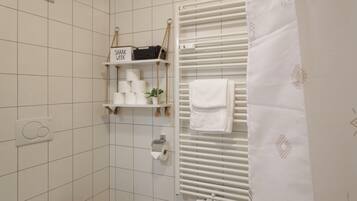 A bathroom with a toilet, a towel rack, a shelf with toiletries, and a radiator.