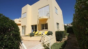 A modern two-story building with a balcony, a small garden, and a paved entrance area. - Ground-floor apartment with spacious terraces, 15 minutes from the marina and Falésia Beach (Quarteira)