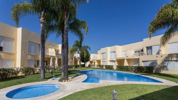 A pool area with a hot tub, palm trees, and a building with balconies. - Ground-floor apartment with spacious terraces, 15 minutes from the marina and Falésia Beach (Quarteira)
