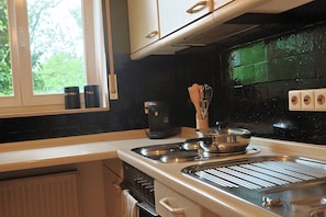 A kitchen with a stove, coffee maker, and tea pots.