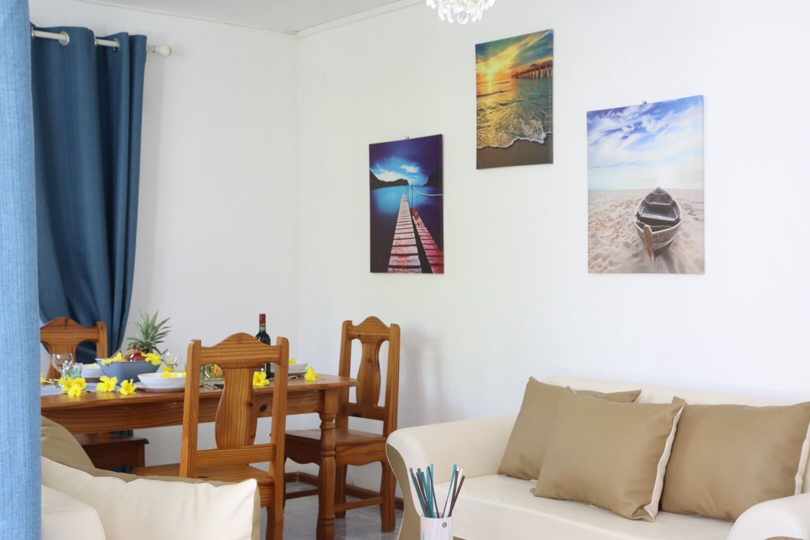 A dining area with a table set for two, wooden chairs, a vase with flowers, and a bottle of wine.