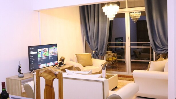 Ein Wohnzimmer mit Flachbildfernseher, Holzstuhl, Sofa und Esstisch.