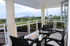 A balcony with a glass table and chairs, offering a view of a mountain and greenery. - Family Luxury Villa with a Panoramic View, Just a Stone's Throw from the Beach (Trou d'Eau Douce)