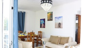 Ein Wohnzimmer mit einer Couch, einem Esstisch mit Stühlen und einer Chandelier.