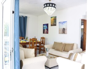 A living room with a sofa, a dining table with chairs, and a chandelier. - Family Luxury Villa with a Panoramic View, Just a Stone's Throw from the Beach (Trou d'Eau Douce)