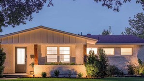 Une maison à deux étages avec un porche à l’avant, un garage et une pelouse bien entretenue.