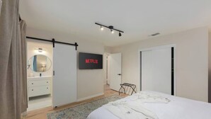 Une chambre à coucher avec un lit, un téléviseur fixé au mur, une armoire et un miroir.