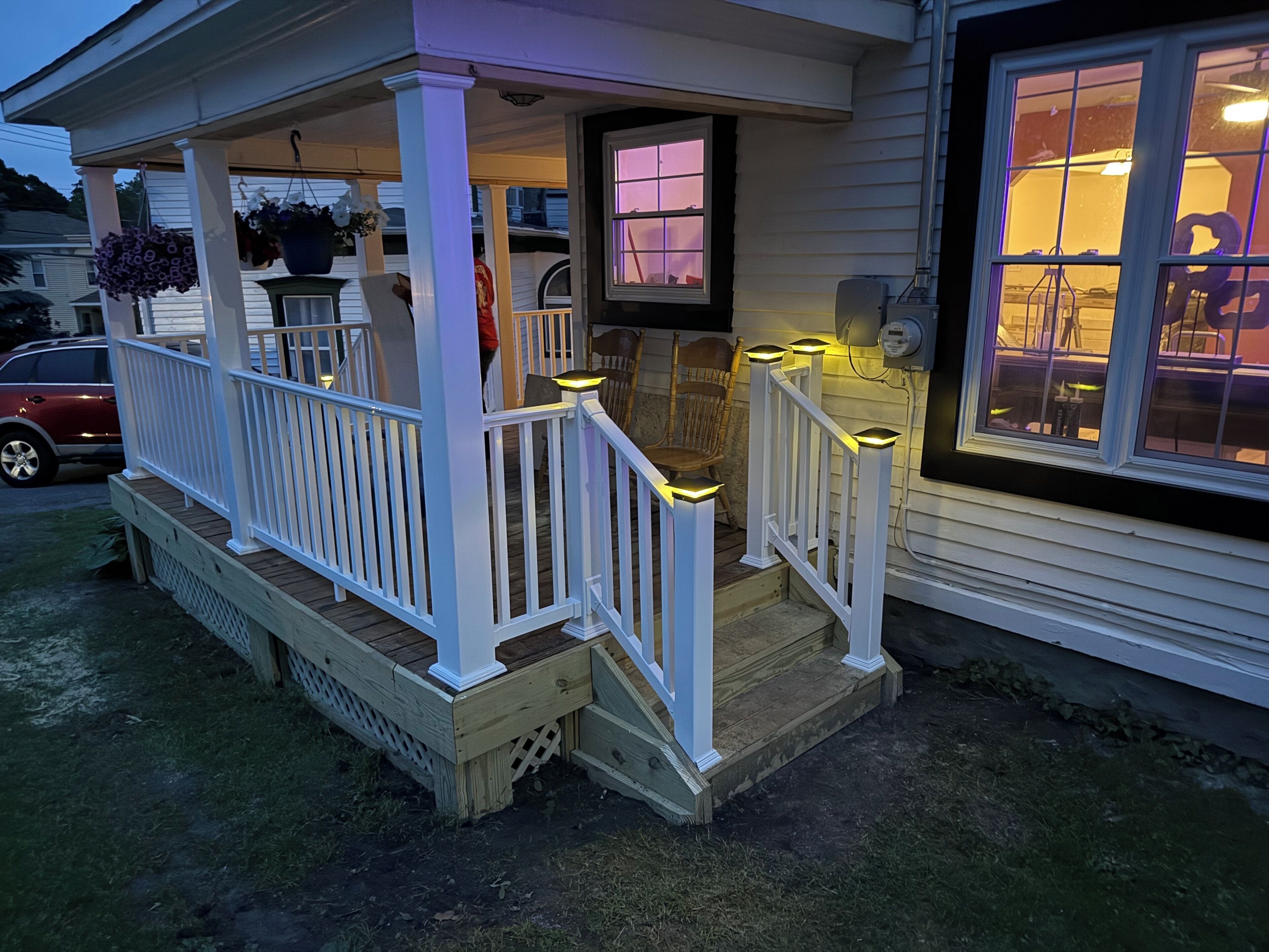 Une véranda avec une balustrade blanche, un banc en bois et une plante en pot.
