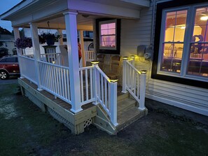 A porch with a white railing, a wooden bench, and a potted plant. - Serene 3-bedroom house with AC in Alexandria Bay (Alexandria Bay)