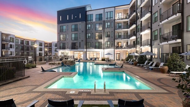 A modern hotel with a rooftop pool area, multiple balconies, and outdoor seating.