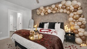 A bedroom with a bed, a nightstand, a wall decorated with balloons, and a ceiling fan.
