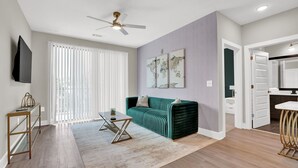 A modern living room with a green sofa, a coffee table, a TV, and a ceiling fan.
