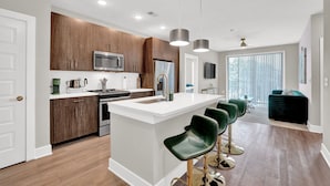 A modern kitchen with wooden cabinets, stainless steel appliances, and a central island with bar stools.