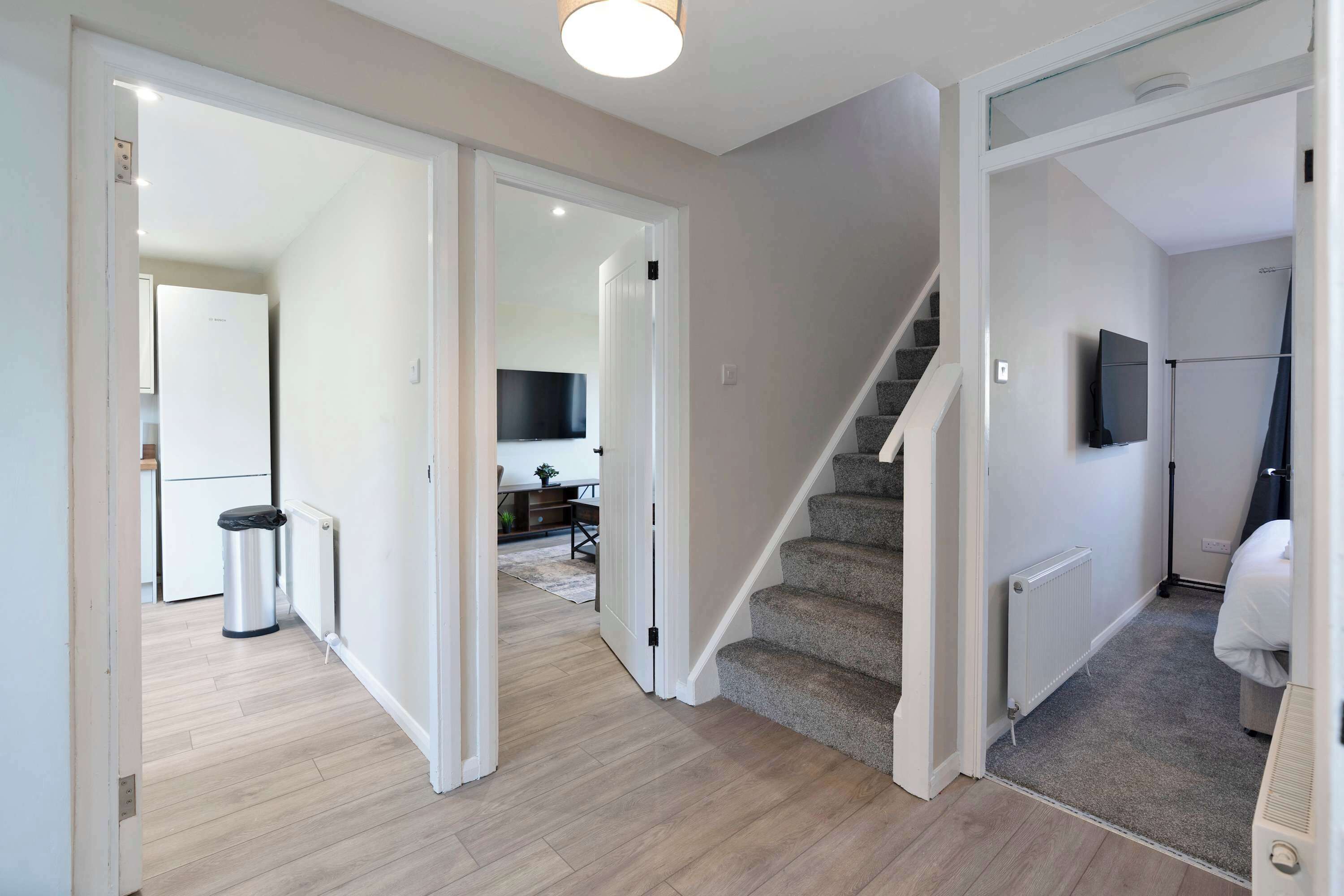 Un interior modern amb una escala, una zona de cuina i un espai de estar amb televisió.