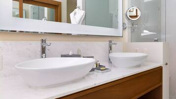 A modern bathroom with two large white sinks, a large mirror, and a wooden vanity.
