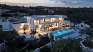 A modern two-story house with a swimming pool, outdoor seating, and a view of the surrounding landscape. - View villas collection - 5 star Villa Blue horizon, pure luxury and comfort (Vinišće)