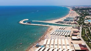 An aerial view of a coastal area with a beach, a marina, and a row of hotel buildings. - Apartment in Side Evrenseki, Hotel Comfort Home Feel (Manavgat)