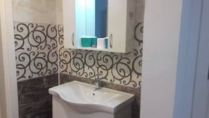 A bathroom with a white sink, a mirror, and decorative wall tiles. - Apartment in Side Evrenseki, Hotel Comfort Home Feel (Manavgat)