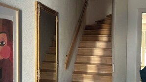 A staircase with wooden steps leading to a landing, a framed artwork on the wall, and a white cabinet. - Cozy 2-bedroom house in tranquil İstanbul with AC (İstanbul)