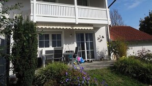 A two-story house with a balcony, a covered porch, and a garden with flowers. - Cozy 2-bedroom house in tranquil İstanbul with AC (İstanbul)