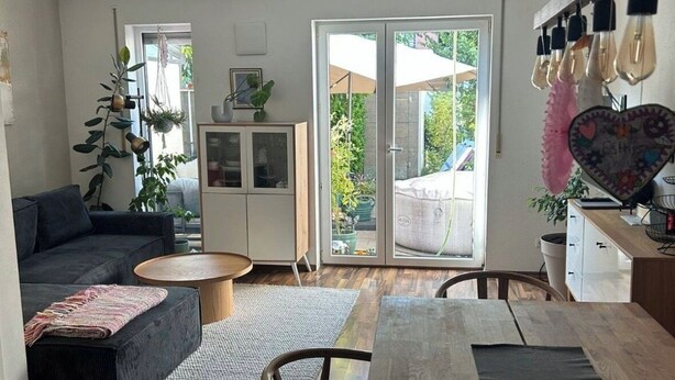 A modern living room with a sofa, coffee table, and dining table. There is a sliding glass door leading to a balcony. - Cozy 2-bedroom house in tranquil İstanbul with AC (İstanbul)
