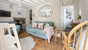 Un salon comprenant un canapé, une petite table, un fauteuil, un téléviseur et une cheminée.
