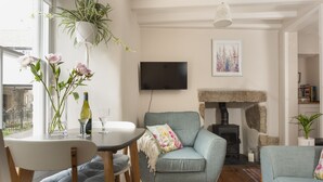 Un salon avec un canapé, une table sur laquelle se trouve une bouteille, un téléviseur et une cheminée.