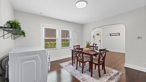 A dining area with a table, chairs, a rug, and a white appliance. - Independence House Near GEHA Field & Fenced Yard (Independence)