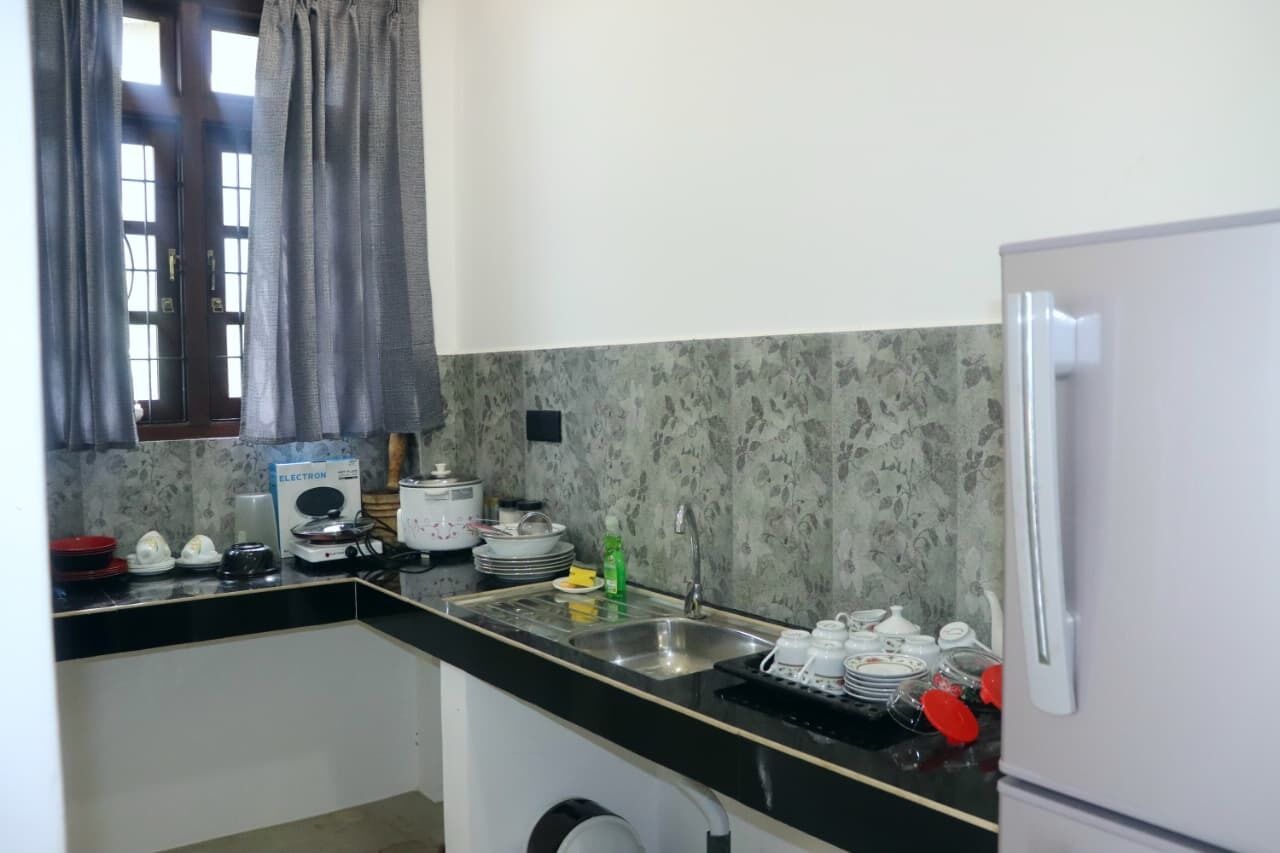 A compact kitchen with a refrigerator, sink, and a microwave.