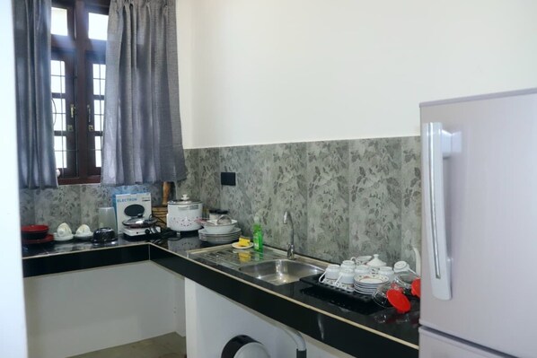 A compact kitchen with a refrigerator, sink, and a microwave.