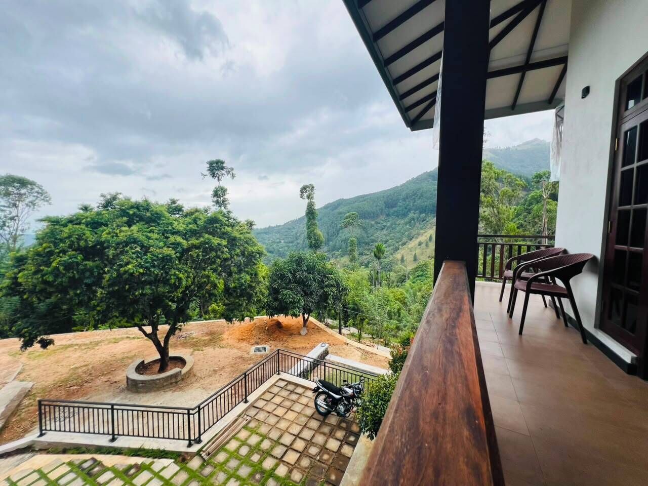 Un balcon avec vue sur un paysage vallonné, une moto et un espace salon.