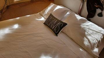 A bed with white bedding and a pillow with the word 'DREAMS' on it.