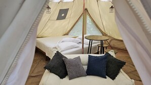 Una carpa con cama, una mesita y una zona de estar con cojines.