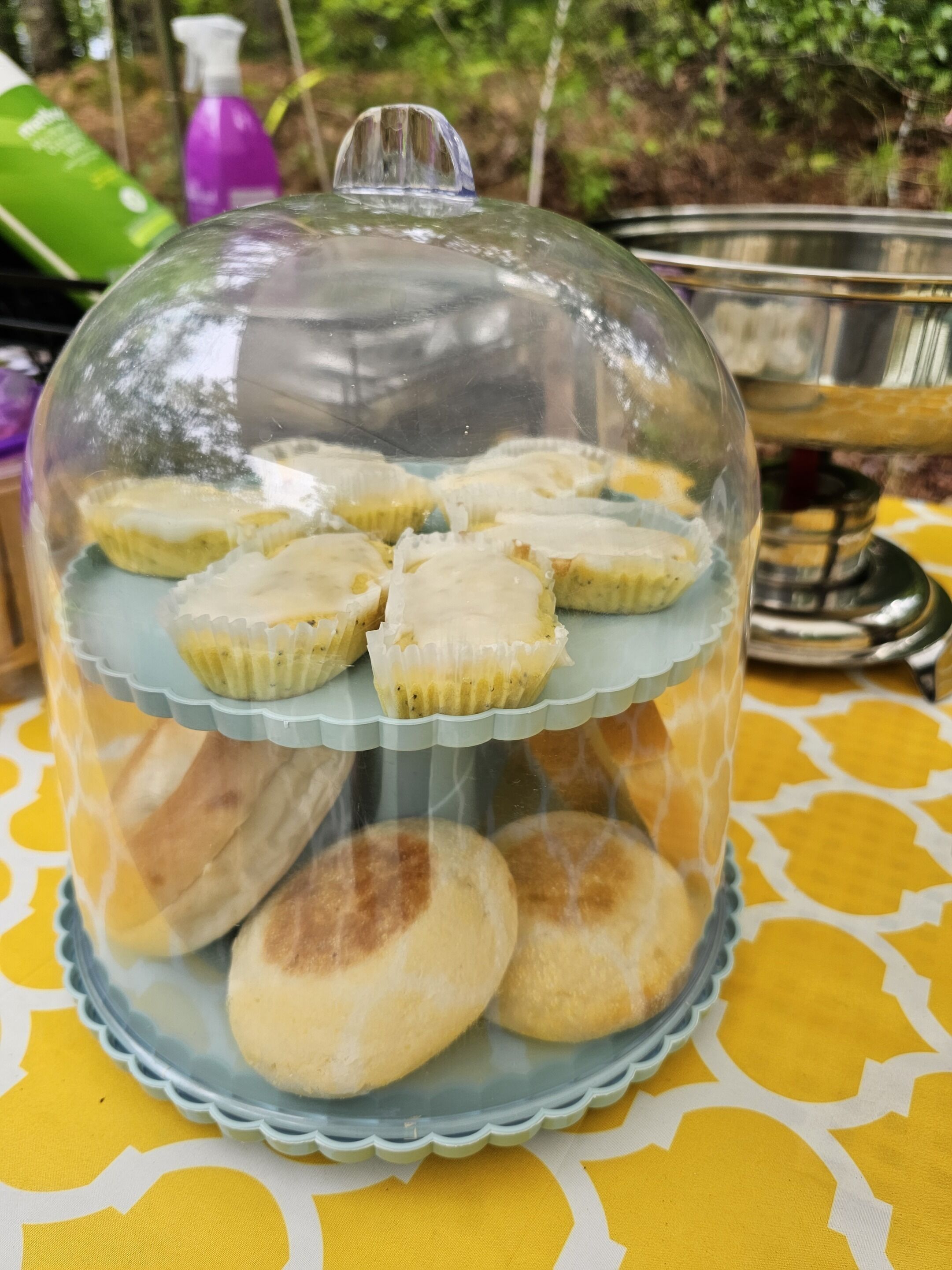 A glass-covered display case with pastries on a patterned tablecloth.