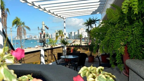 A terrace with a view of the sea, potted plants, and outdoor furniture.