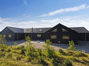 A modern building with a gravel driveway and surrounding vegetation. - 5 Star Holiday Home in Norre Nebel (Norre Nebel)