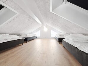 A spacious attic bedroom with two beds, wooden flooring, and a sloped ceiling. - 5 Star Holiday Home in Norre Nebel (Norre Nebel)