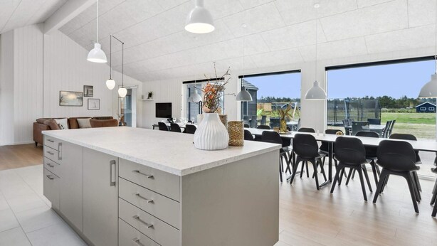 A modern kitchen with a large island, pendant lighting, and a view to the outdoors. - 5 Star Holiday Home in Norre Nebel (Norre Nebel)