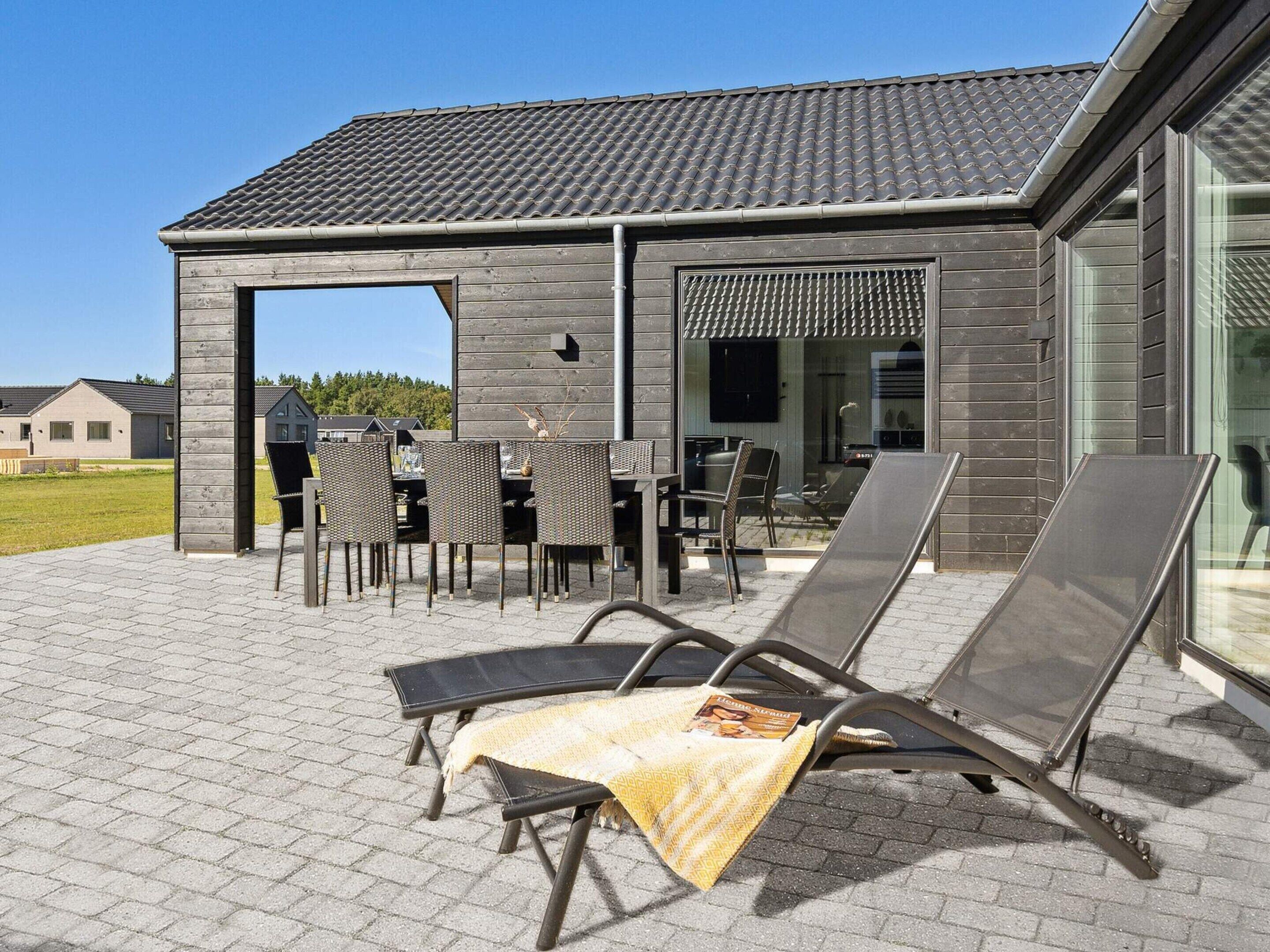 Une terrasse avec des meubles d’extérieur, un espace salon couvert et un bâtiment doté d’un toit en tuiles.