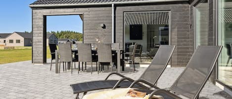 A patio with outdoor furniture, a covered seating area, and a building with a tiled roof.