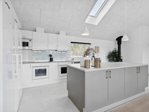 A modern kitchen with white cabinetry, a central island, and a skylight. - 5 Star Holiday Home in Norre Nebel (Norre Nebel)