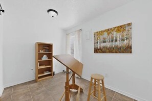 A room with a wooden desk, a stool, a bookshelf, and a painting on the wall. - 3 bedroom house with AC in Albuquerque near airport, 5 minutes off I-40 &I-25 (Albuquerque)