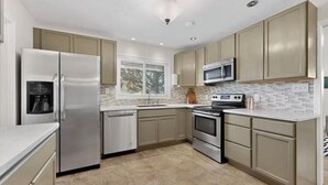 Una cocina moderna con electrodomésticos de acero inoxidable, armarios color beige y un salpicadero de azulejos.