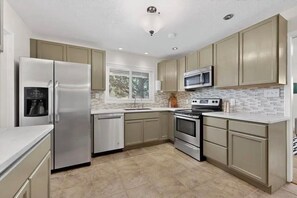 A modern kitchen with stainless steel appliances, beige cabinetry, and a tiled backsplash. - 3 bedroom house with AC in Albuquerque near airport, 5 minutes off I-40 &I-25 (Albuquerque)