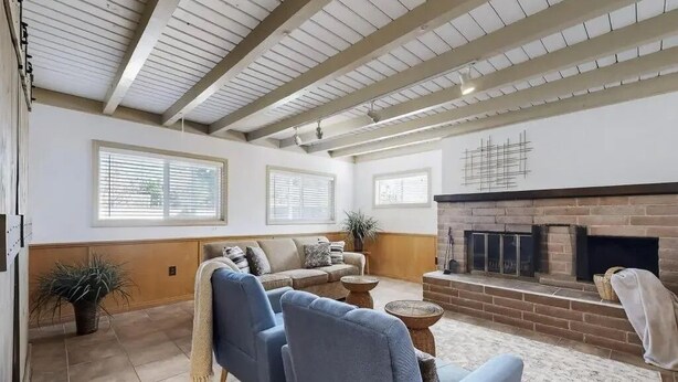 Una sala de estar con chimenea, sofás y un techo con vigas a la vista.