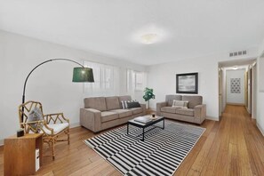 A modern living room with two sofas, a coffee table, a striped rug, a floor lamp, and a framed picture on the wall. - 3 bedroom house with AC in Albuquerque near airport, 5 minutes off I-40 &I-25 (Albuquerque)