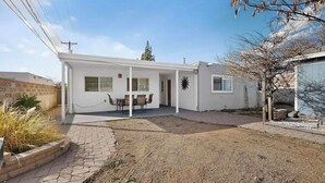 Un edificio moderno y blanco con un patio, una mesa de comedor y sillas.