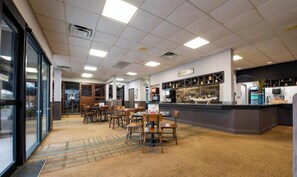A hotel lobby with a reception desk, seating area, and a view through the glass doors. - Orlando Studio Near Universal with Pools ,Balcony Resort Ameneties (Orlando)